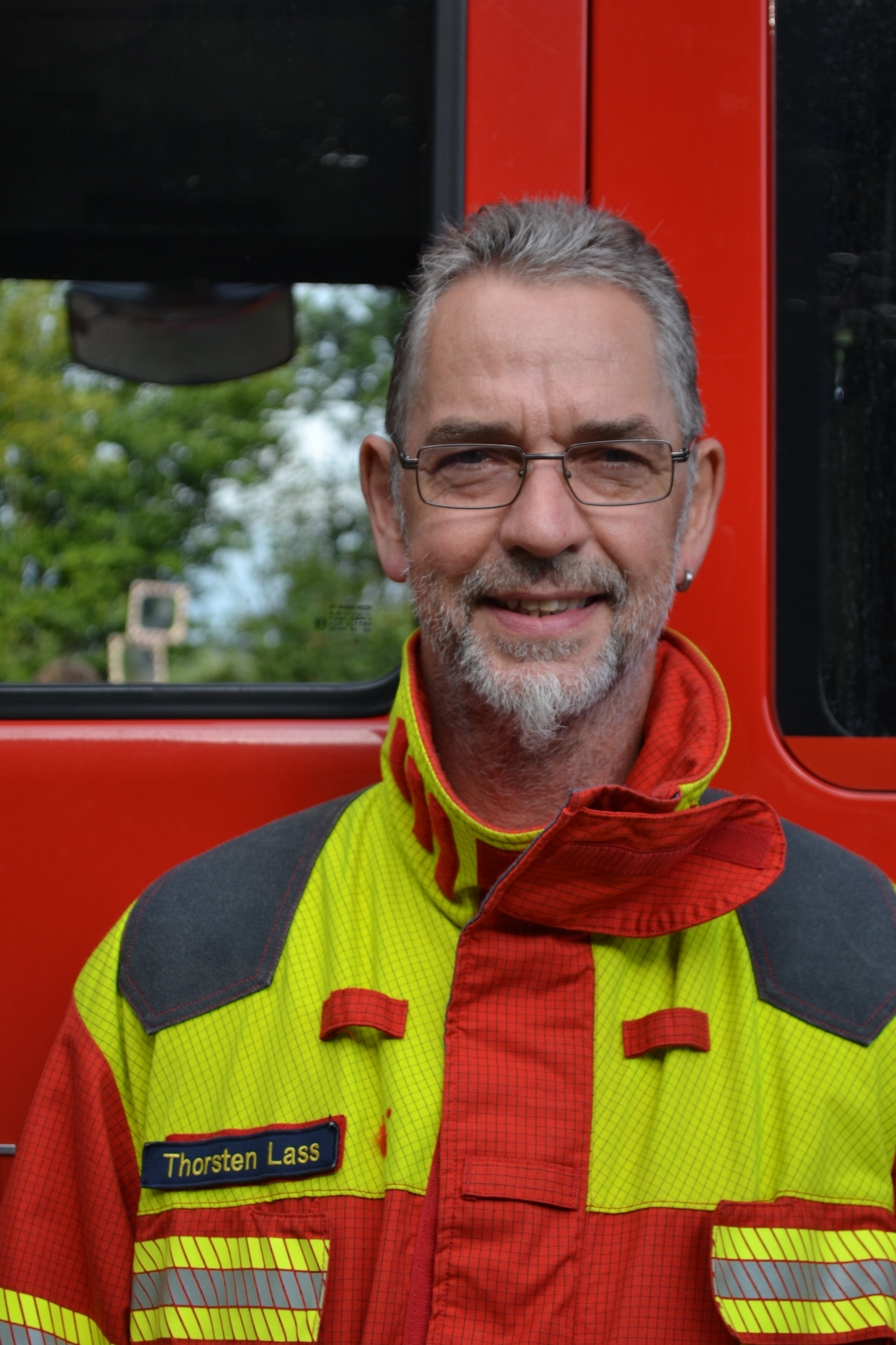 Der stellvertretende Jugendwart Thorsten Lass vor einem Feuerwehrfahrzeug.